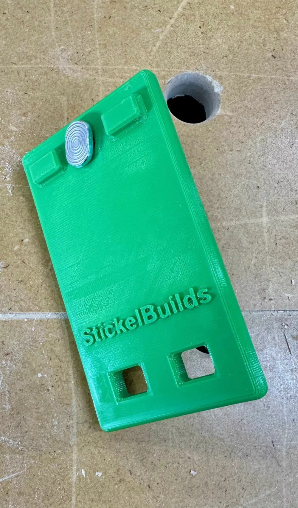 green quick clamp storage hangar on a workbench. text embossed on the product says Stickel Builds