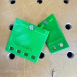 green quick clamp storage hangars on a workbench. text embossed on the product says Stickel Builds