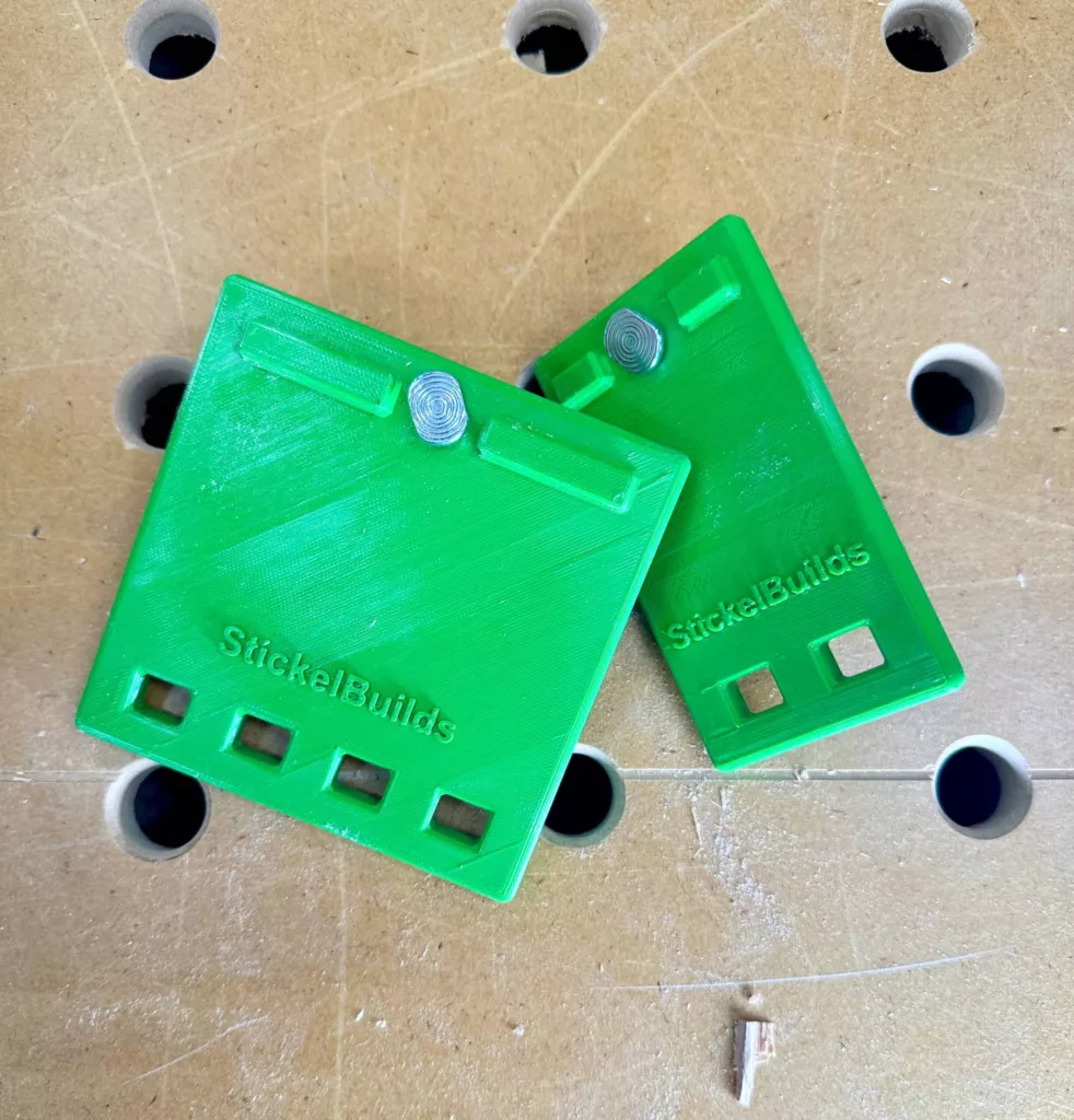 green quick clamp storage hangars on a workbench. text embossed on the product says Stickel Builds